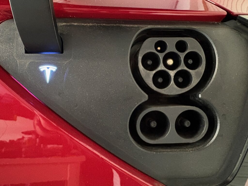 A CCS2 Charge Port on a Red 2021 Tesla Model 3 SR+