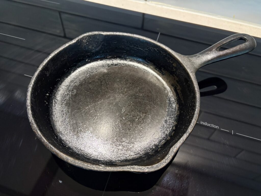 An old cast iron skillet on an induction cooktop